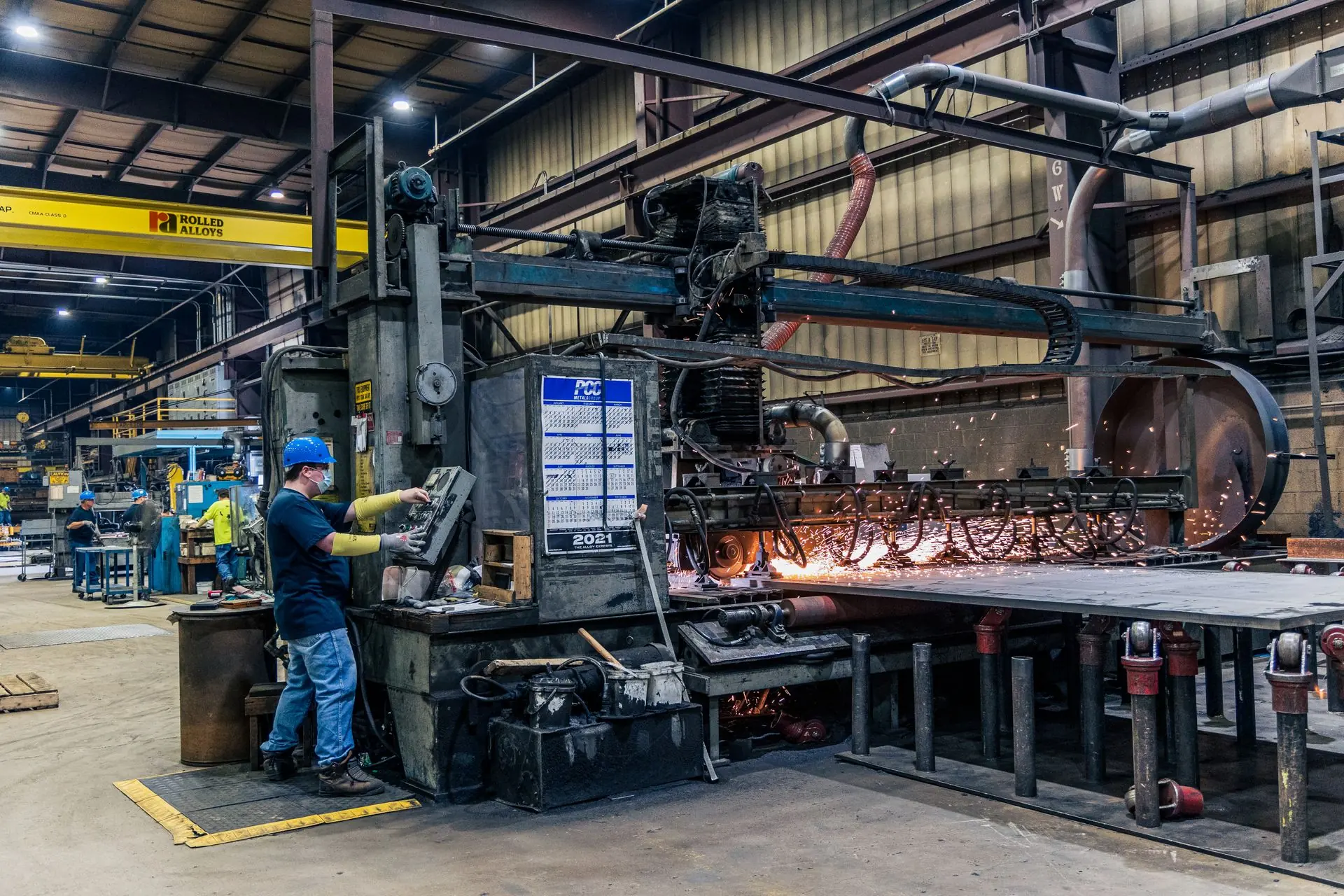 A factory worker operating industrial cutting machinery on a production floor.